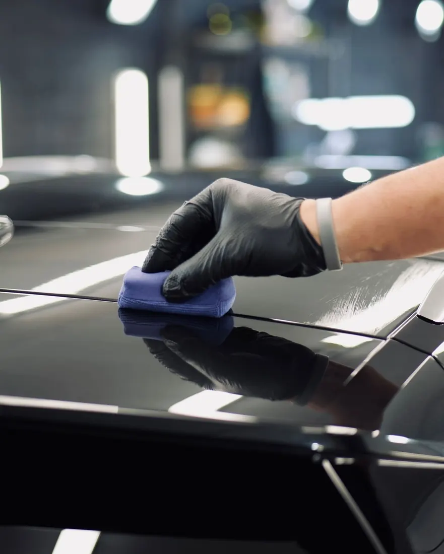 Protección acrílica para autos: aplicación de recubrimiento cerámico sobre el cofre negro de un auto