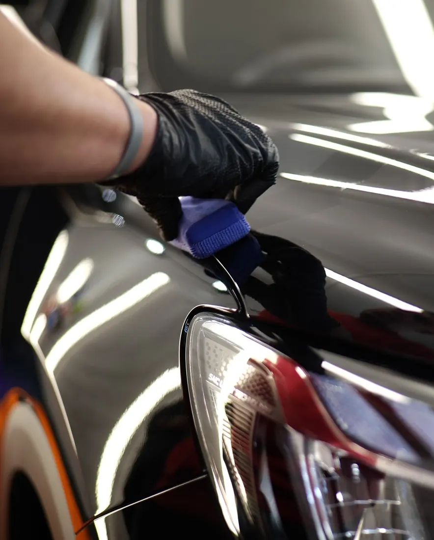 Protección acrílica para autos: aplicación de cerámico cerca de la calavera de un auto