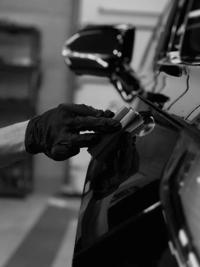 Encerado de autos: aplicación de sellador con aplicador en una pintura oscura, blanco y negro