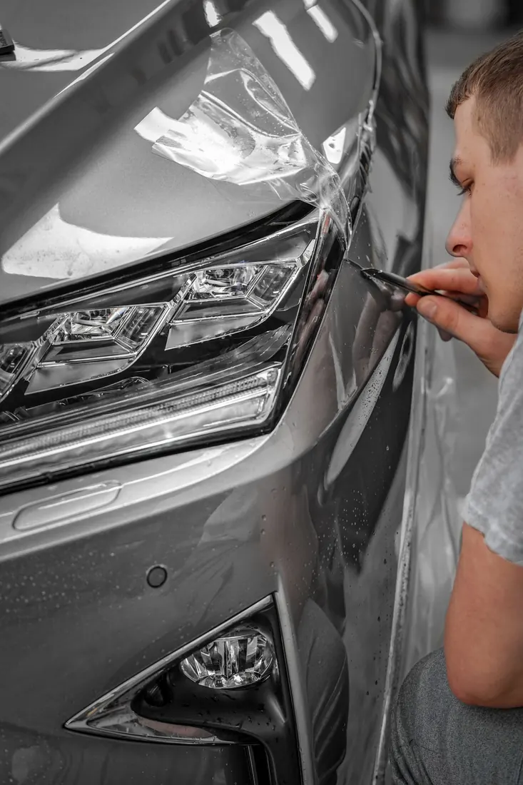 Restauración de faros: instalación de película PPF en el faro y costado de un auto gris
