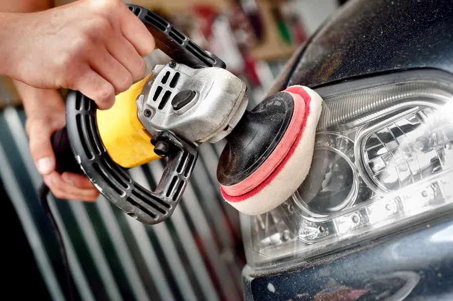 Blog de detallado automotriz: el pulido quita rayones - pulido de faro con máquina y esponja, manos trabajando sobre el auto