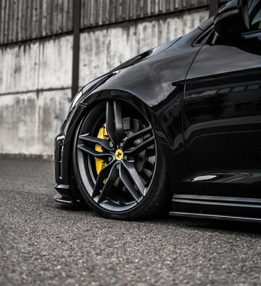 Detailing llantas: rin gris con caliper amarillo en un auto negro bajo