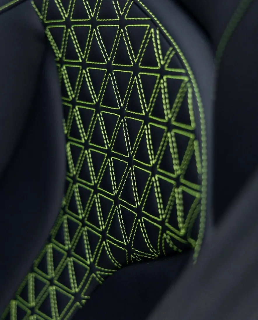 Lavado de vestiduras precio: detalle de costura verde en el respaldo de un asiento negro
