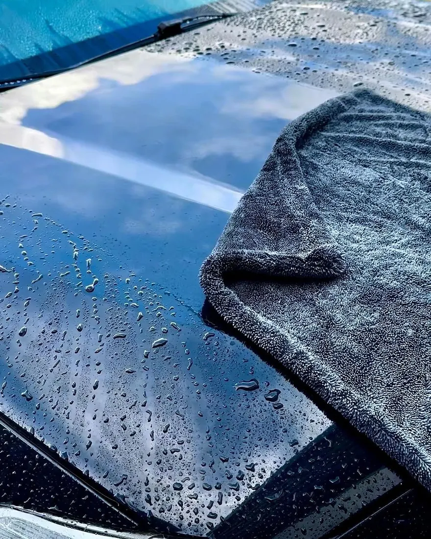 Pulido de parabrisas precio: toalla de microfibra sobre un cofre negro con gotas de agua